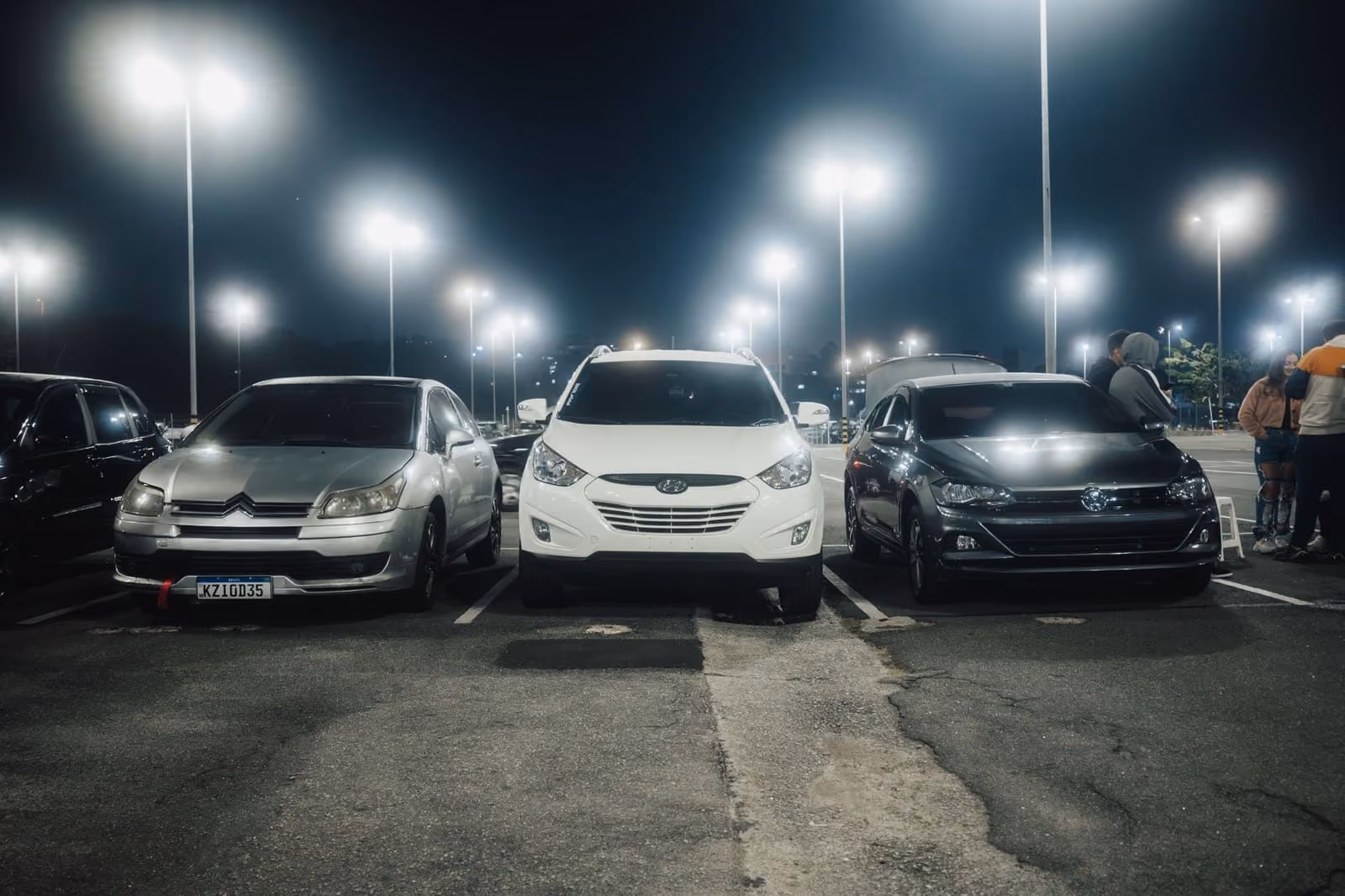 Cars parked in rows under streetlights on a lot at night
